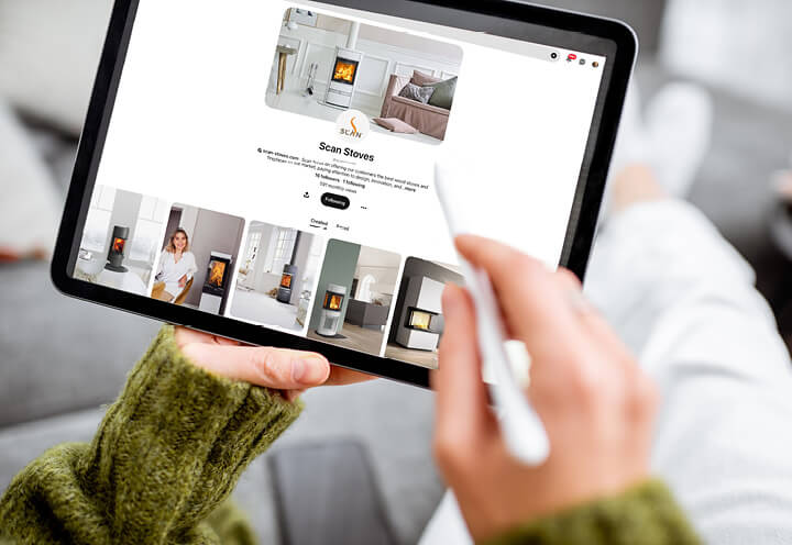 Nærbilde av hender som holder et nettbrett og scroller på pinterest