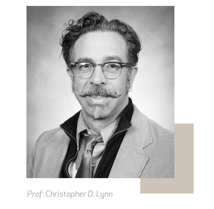 Black & white portrait of Professor Christopher D. Lynn an smiling man with wavey hair, glasses and a beard