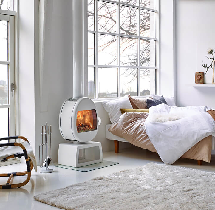 White fireplace Scan 66 with square stands in a white bedroom with large windows by a bed