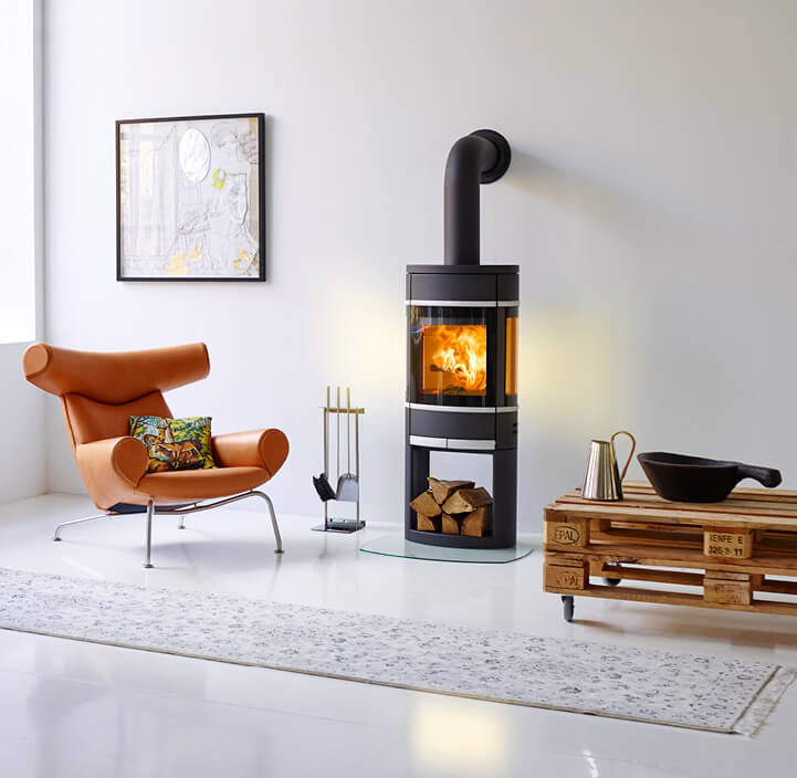 Black fireplace Scan 68 burning in a white room with a cognac-colored chair and a pallet table next to it