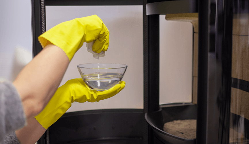 hand with yellow gloves holding bowl of water