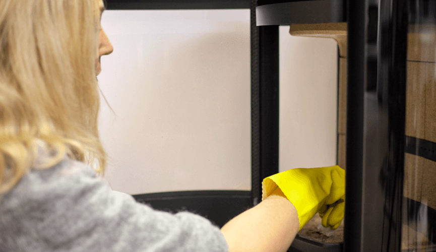 Woman with yellow gloves clean ash from the fireplace