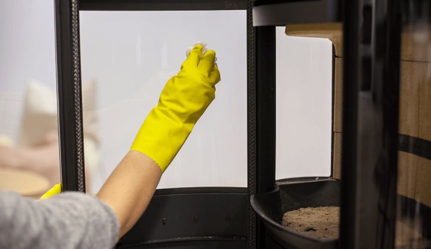 Hand with yellow gloves cleaning the fireplace glass 