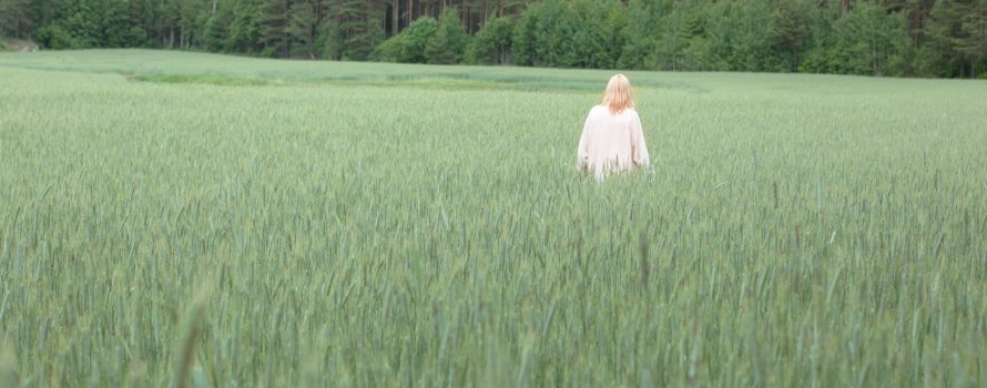 Blonde woman in white dress standing in a green field