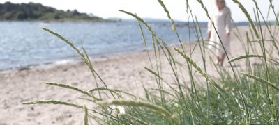 Woman in white dress walking along a Danish beach