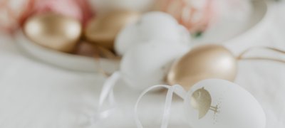 Top picture: Table with white tablecloth and dish with painted Easter eggs in pink, white and gold