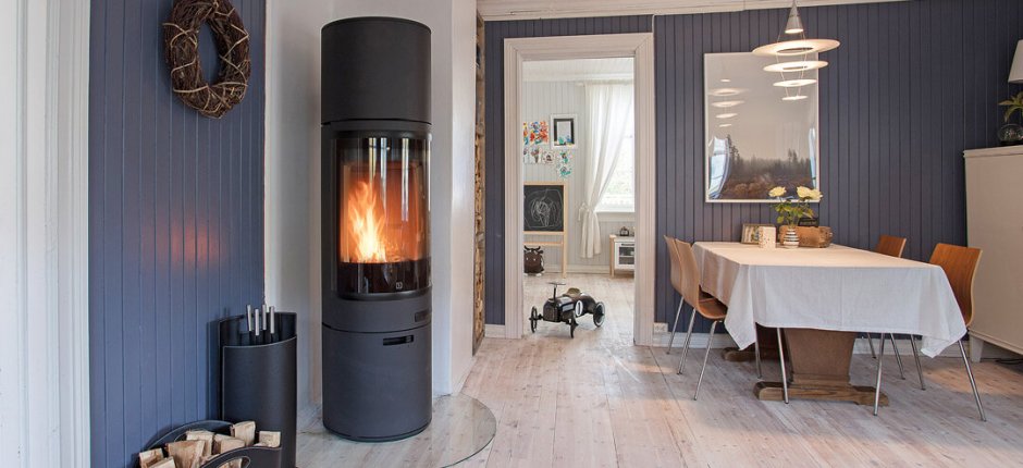 The black fireplace which is close to the blue color wall heats the room in a house.