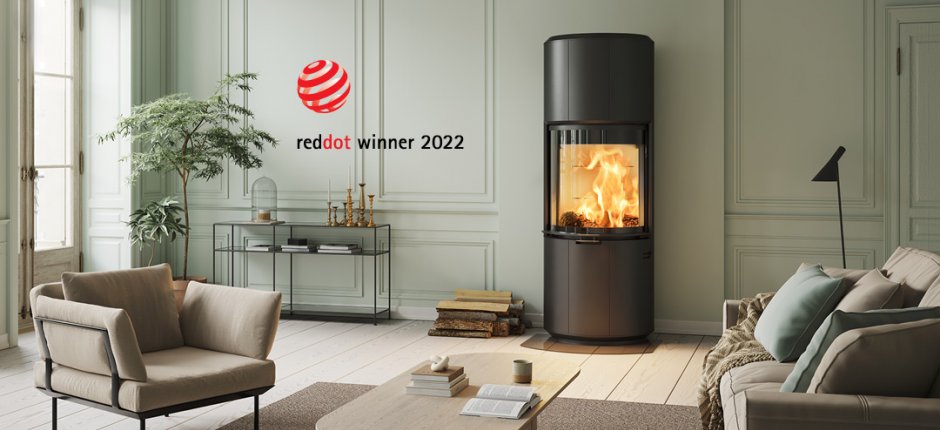 Big black stove Scan 87 Award winner of Red Dot Design Award in a sage green room with a brown sofa and chair in front