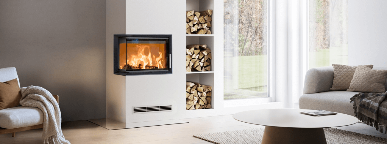 Modern built-in fireplace Scan 5103 FL with glass front and left side, integrated into a bright interior with wood niche and visible flames.