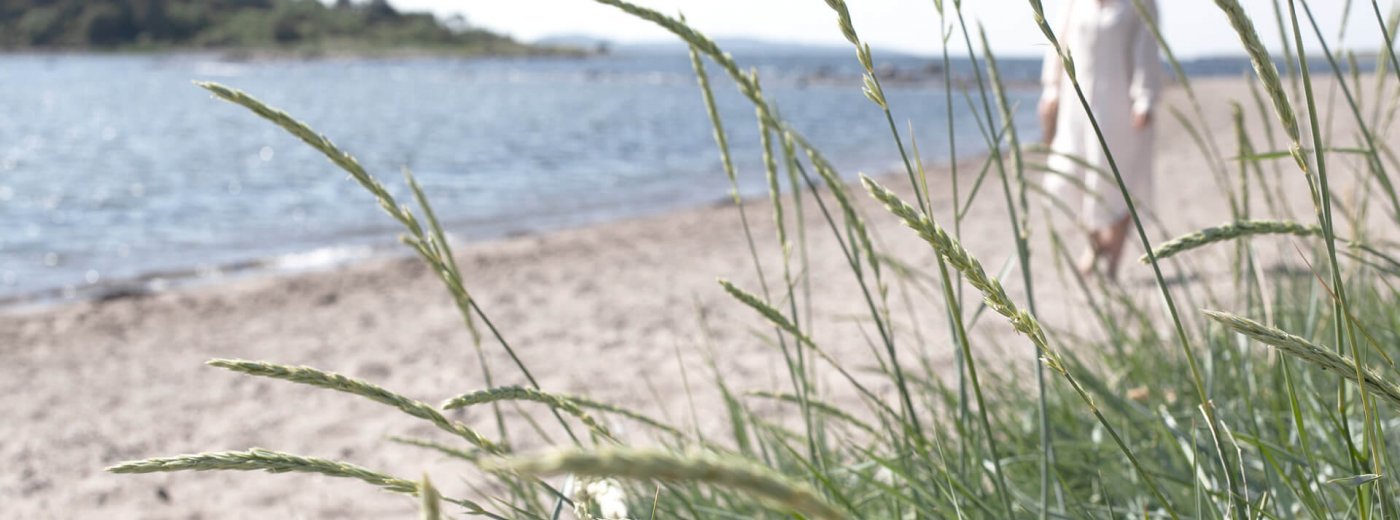 Woman in white dress walking along a Danish beach