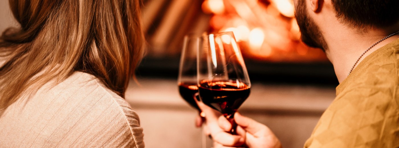 Couple drinking wine in front of the fireplace