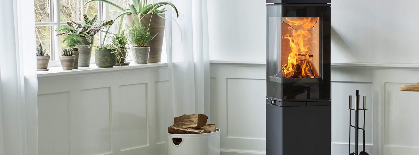 The high black colour fireplace is close the white wall and window.