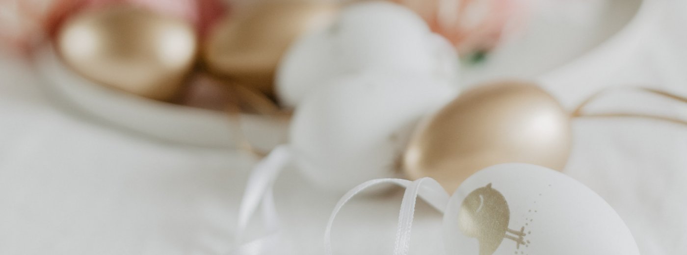 Top picture: Table with white tablecloth and dish with painted Easter eggs in pink, white and gold