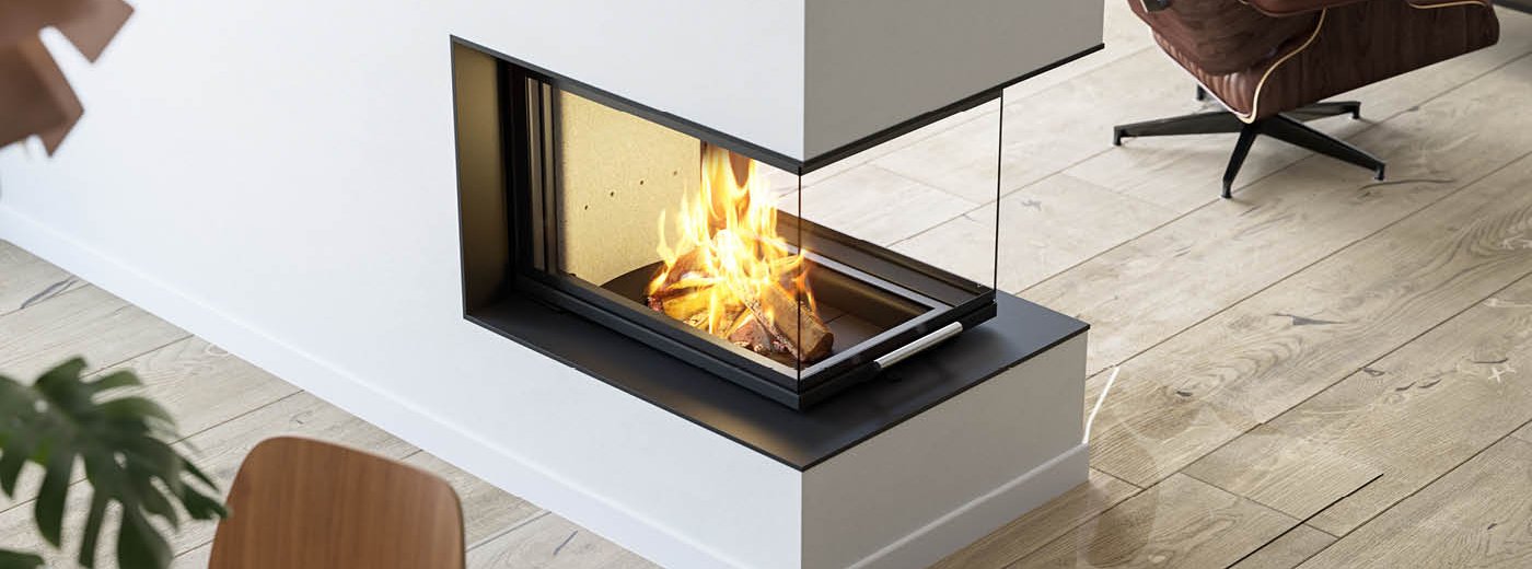 Picture taken from above of large fireplace insert Scan 5005 FRL with glass on three sides and sliding door on rustic wooden floor and brown leather chair next to it