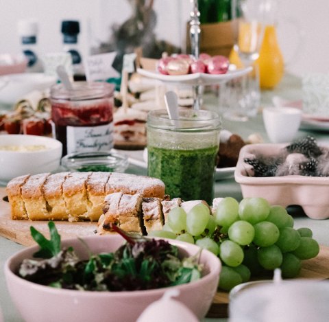 Easter Decorated table with pink bowls and buffet with bread, grapes, pesto, and much more