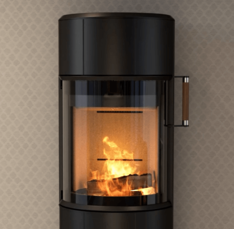Close-up of black round wood-burning stove Scan 67 with flames in front of wall with beige checkered wallpaper