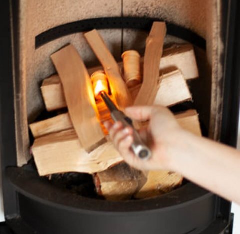 Stacked fire in a Scan 83-2 wood stove and a woman's hand lighting it
