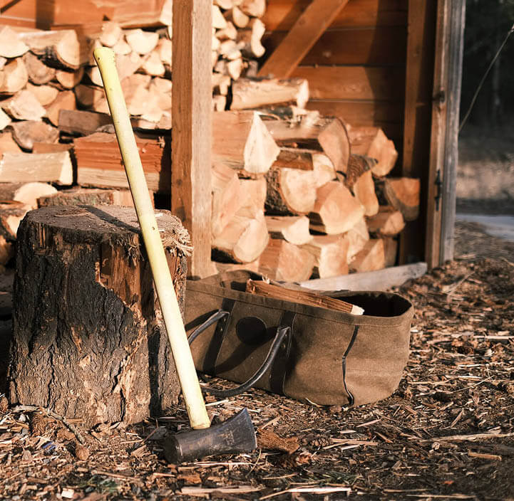 Øks står lent mot en hoggestabbe ved et åpent vedskjul