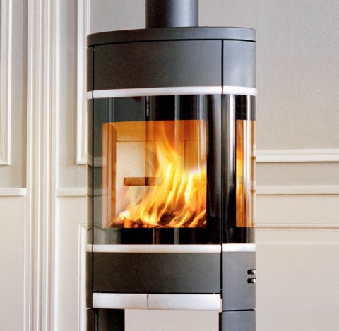 Black oval wood-burning stove with side glass and open base, aluminum handle and trim for wood Scan 68-12 in a classic room with light walls